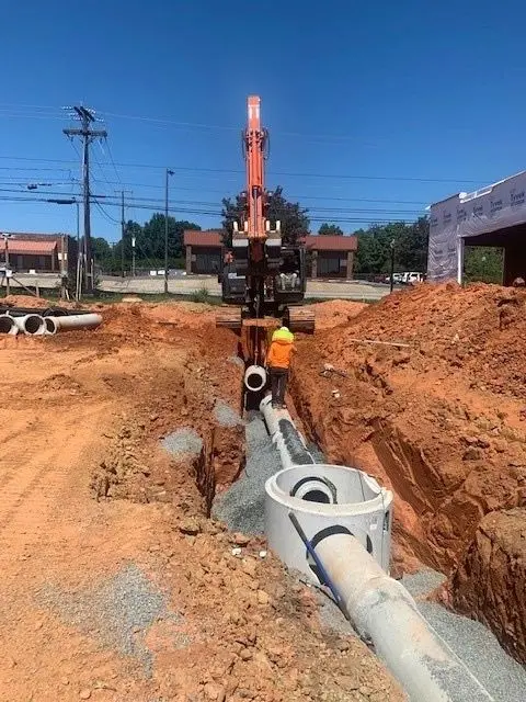 Crew installing concrete storm drain pipe on a construction site